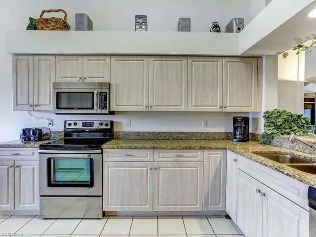 a kitchen with granite countertop a stove top oven microwave and cabinets