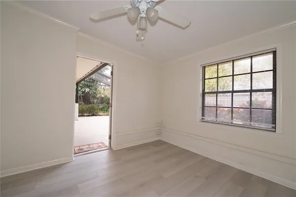an empty room with wooden floor chandelier and windows