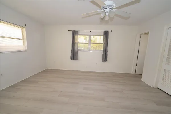 an empty room with chandelier fan and windows