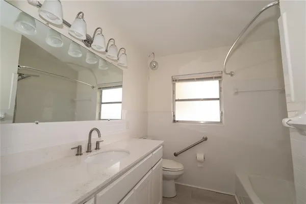 a bathroom with a granite countertop sink a toilet and a mirror