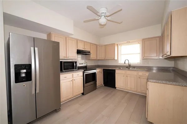 a kitchen with stainless steel appliances granite countertop a refrigerator a sink dishwasher a stove with white cabinets