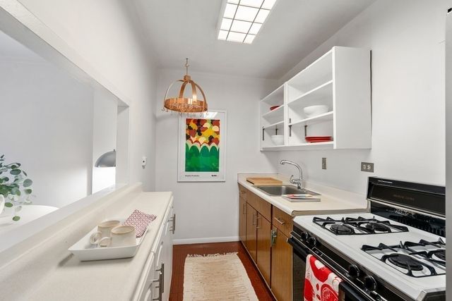 a kitchen with stainless steel appliances granite countertop a stove a sink dishwasher and cabinets with wooden floor