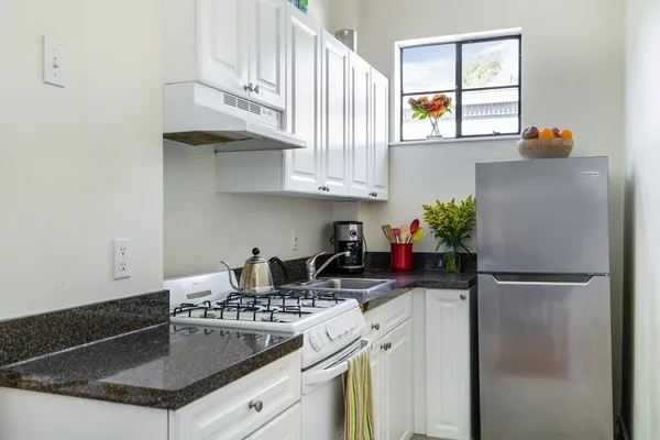 a kitchen with stainless steel appliances granite countertop a stove a refrigerator and a sink