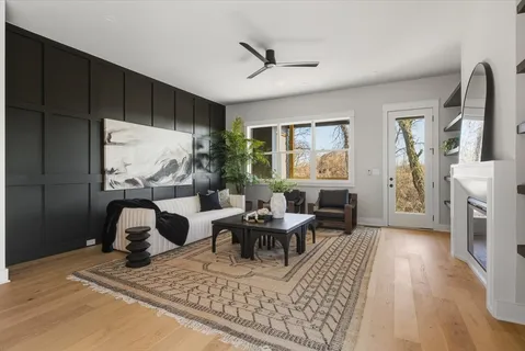 a living room with furniture a large window and wooden floor