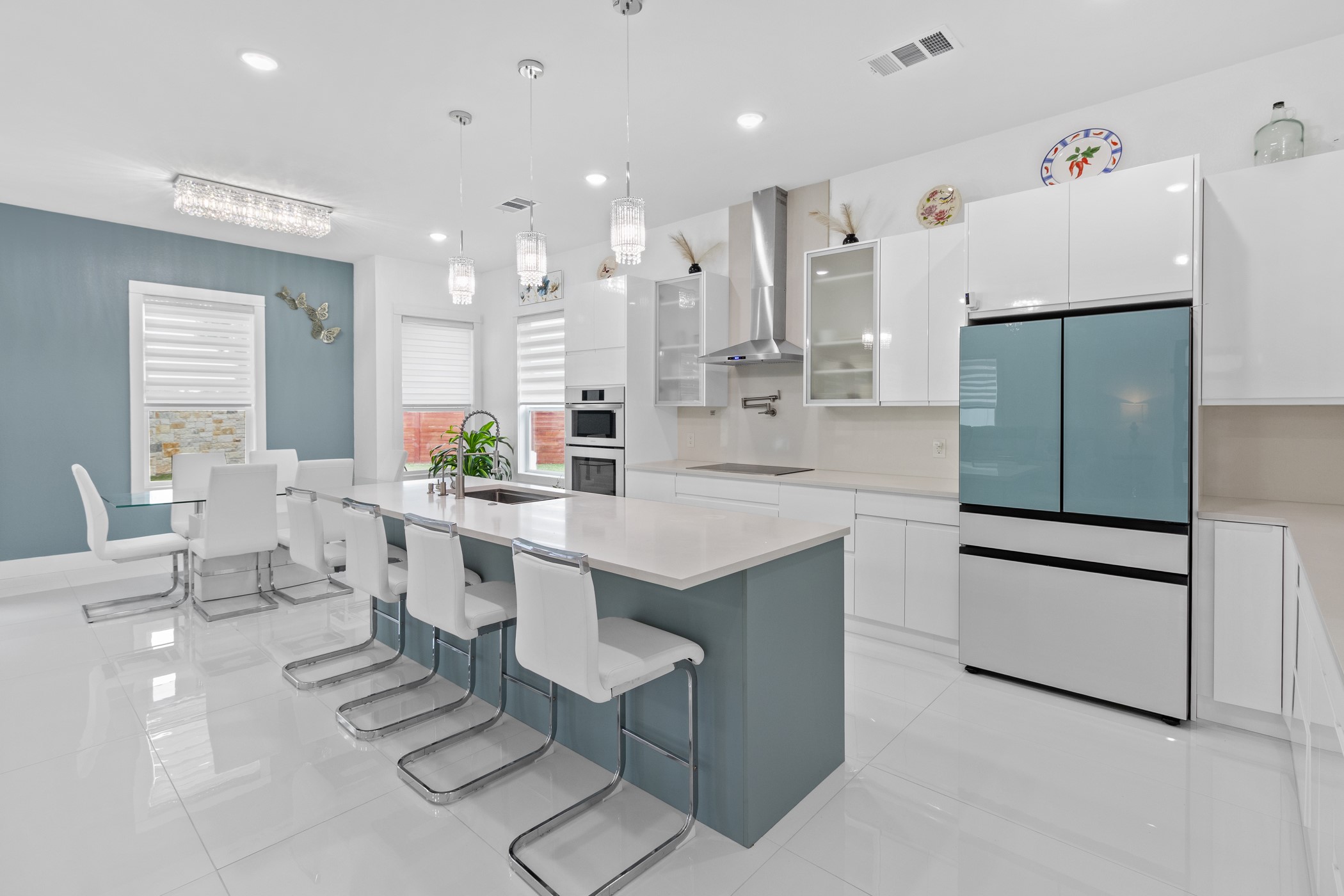 123 Zacate Street Elgin, TX 78621 - Photo 19 of 33 Contemporary kitchen featuring a large center island with seating, white high-gloss cabinetry, and a stainless steel range hood