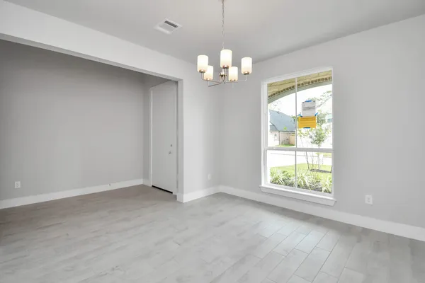 a view of an empty room with a chandelier fan