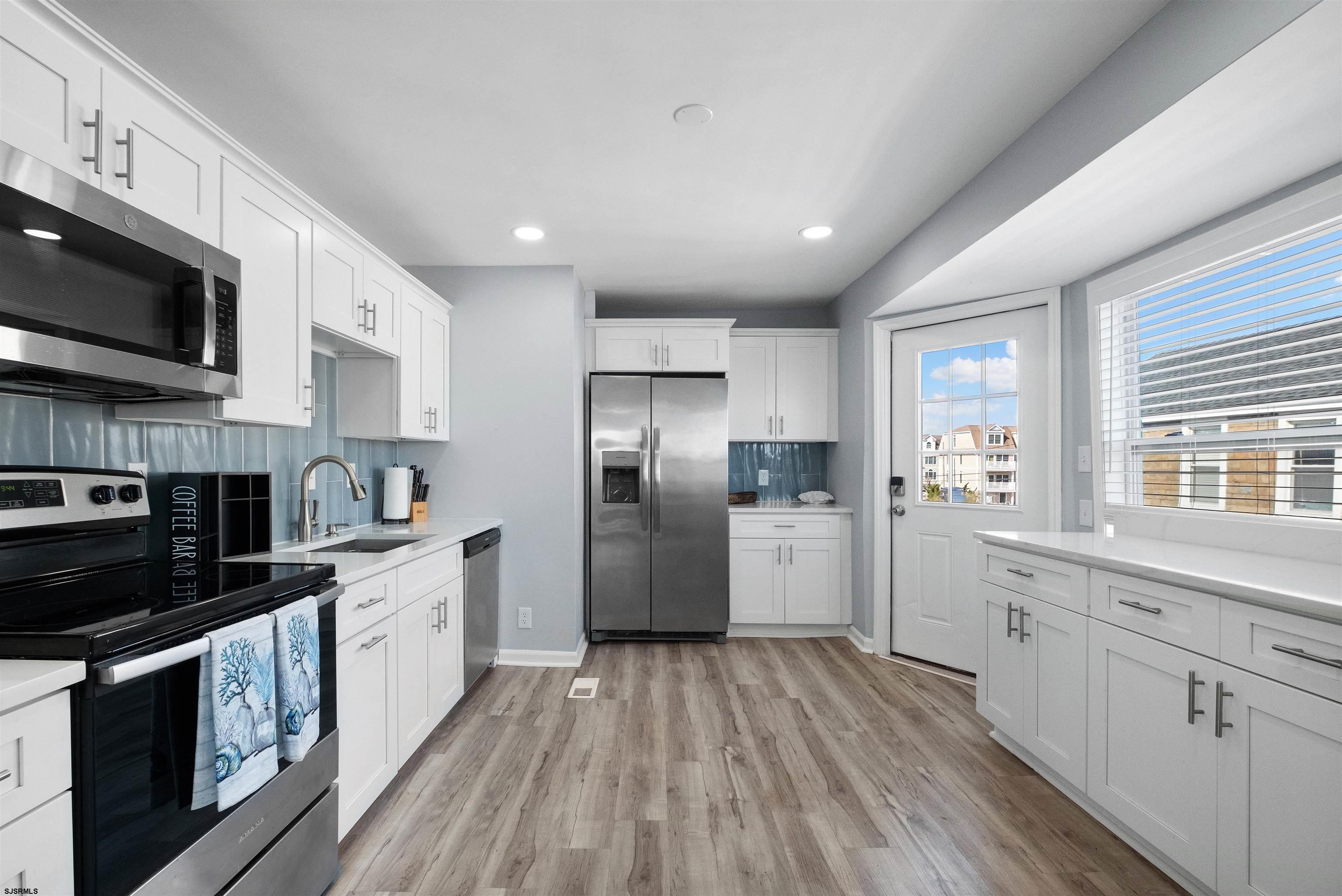 69 North Harrisburg Avenue, Unit 4 Atlantic City, NJ 08401 - Photo 15 of 25 a kitchen with stainless steel appliances granite countertop a refrigerator a stove top oven a sink dishwasher and white cabinets with wooden floor