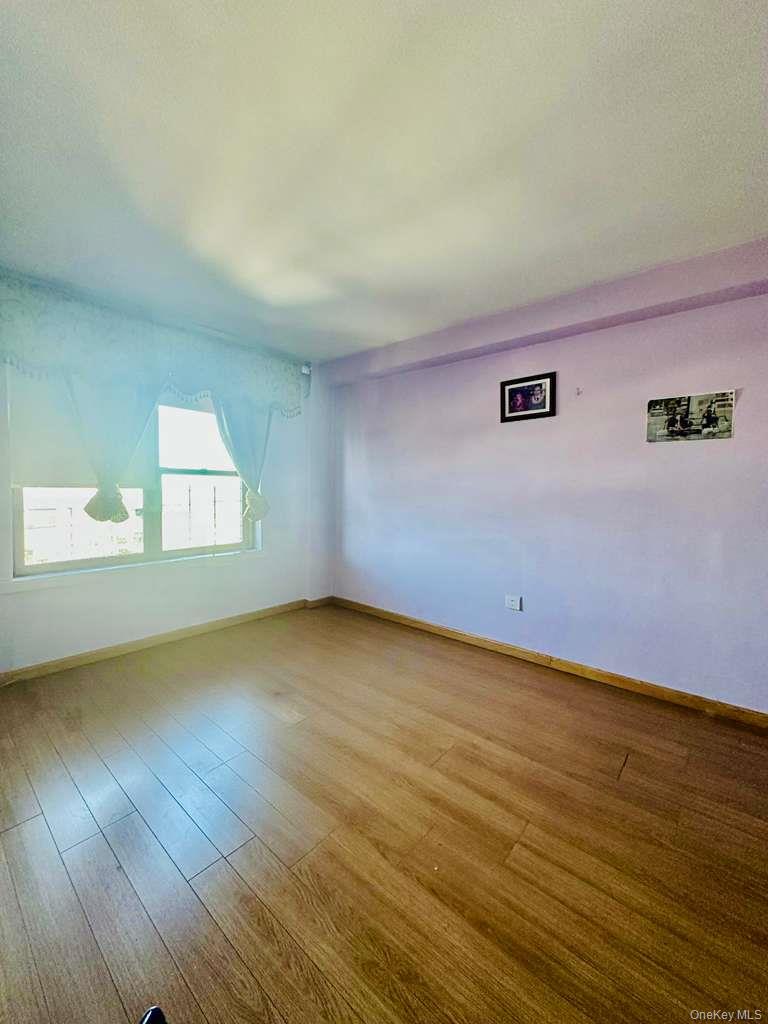 99-60 63rd Road, Unit 7Q Queens, NY 11374 - Photo 12 of 12 an empty room with wooden floor and windows