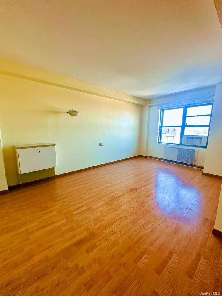 99-60 63rd Road, Unit 7Q Queens, NY 11374 - Photo 7 of 12 an empty room with wooden floor and windows