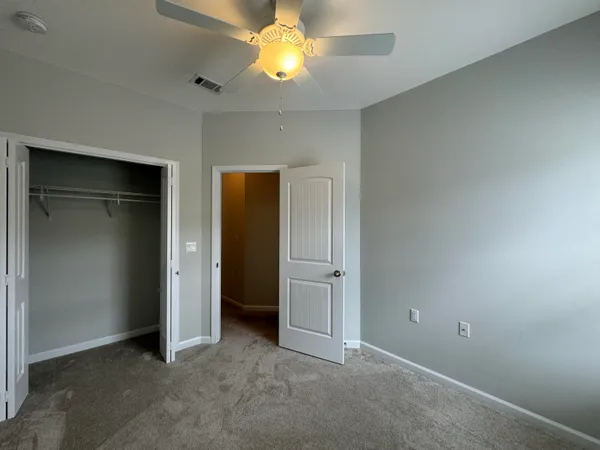 an empty room with closet and a chandelier fan