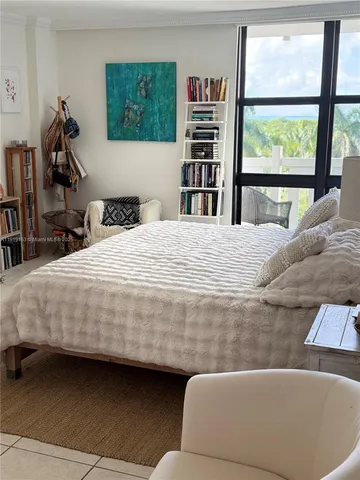 a bedroom with a bed a dresser and a large window