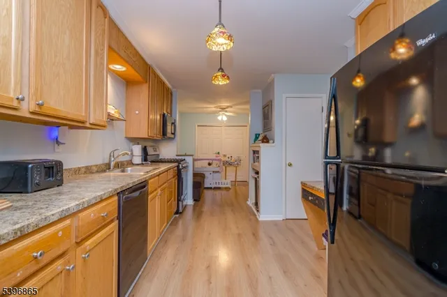 a kitchen with granite countertop a refrigerator a stove top oven a sink dishwasher and cabinets with wooden floor