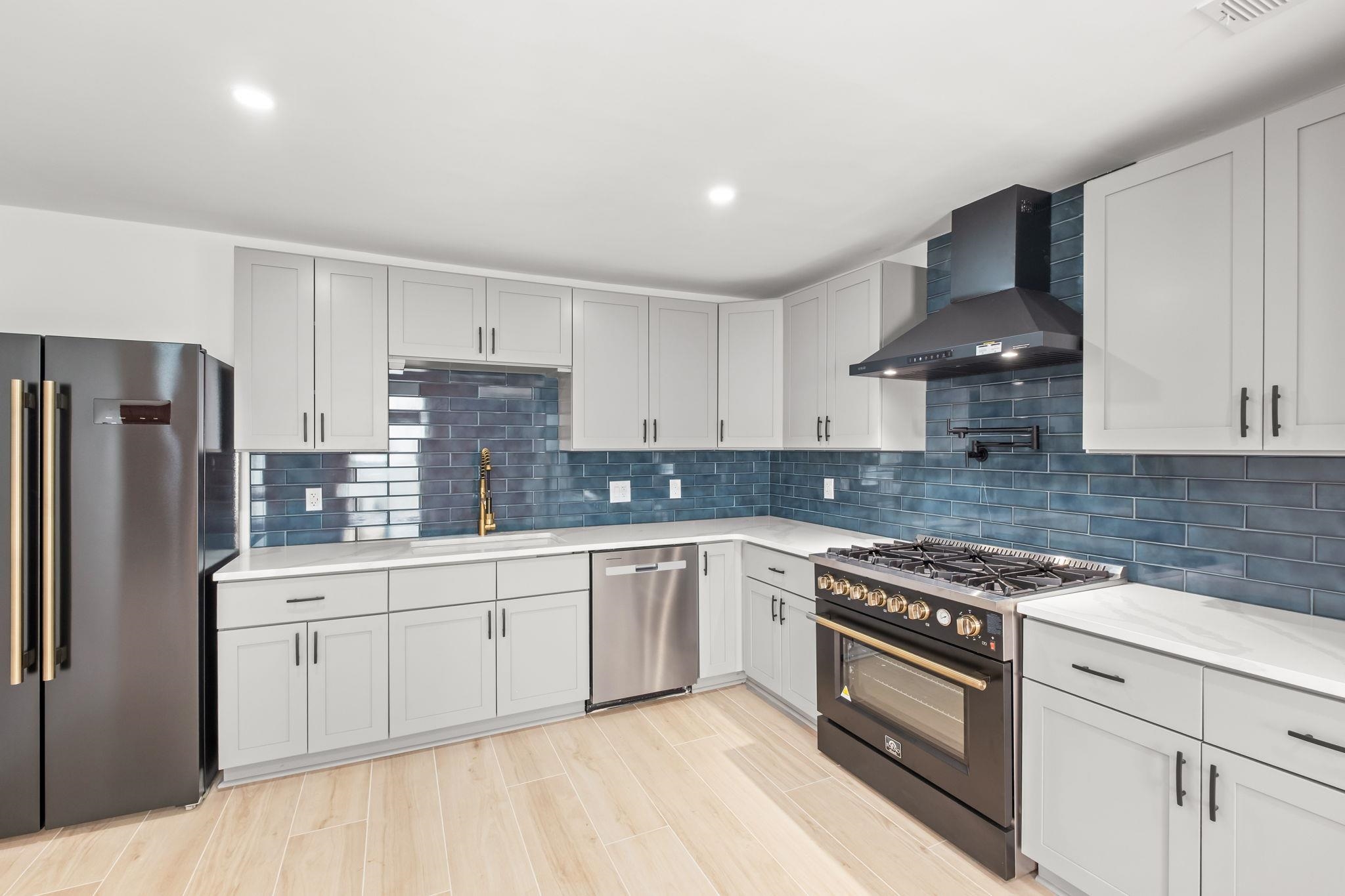 6224 Benjestown Road Memphis, TN 38127 - Photo 11 of 38 Kitchen with high end range, freestanding refrigerator, stainless steel dishwasher, white cabinetry, and wood tiled floors