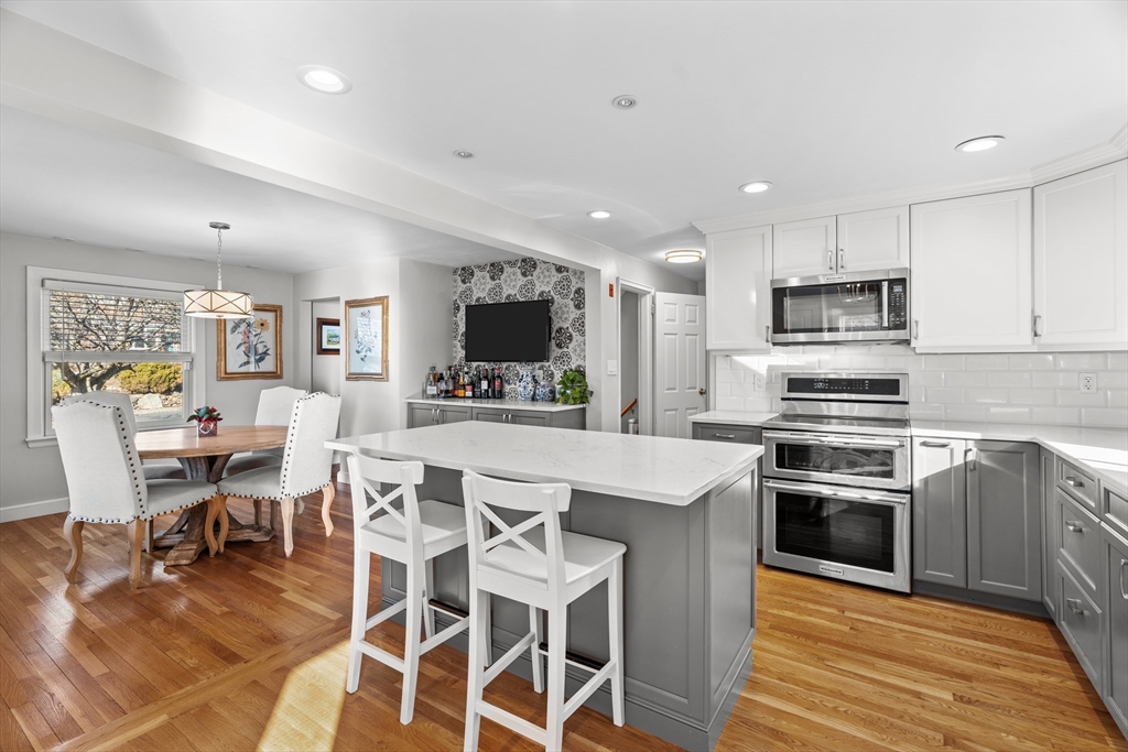 21 Oakvale Road Framingham, MA 01701 - Photo 7 of 42 a kitchen with stainless steel appliances kitchen island granite countertop a stove top oven a sink dishwasher a dining table and chairs with wooden floor