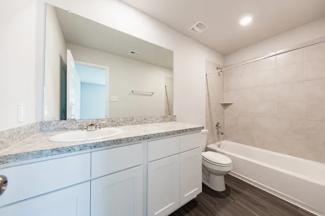 a bathroom with a granite countertop sink a toilet and bathtub