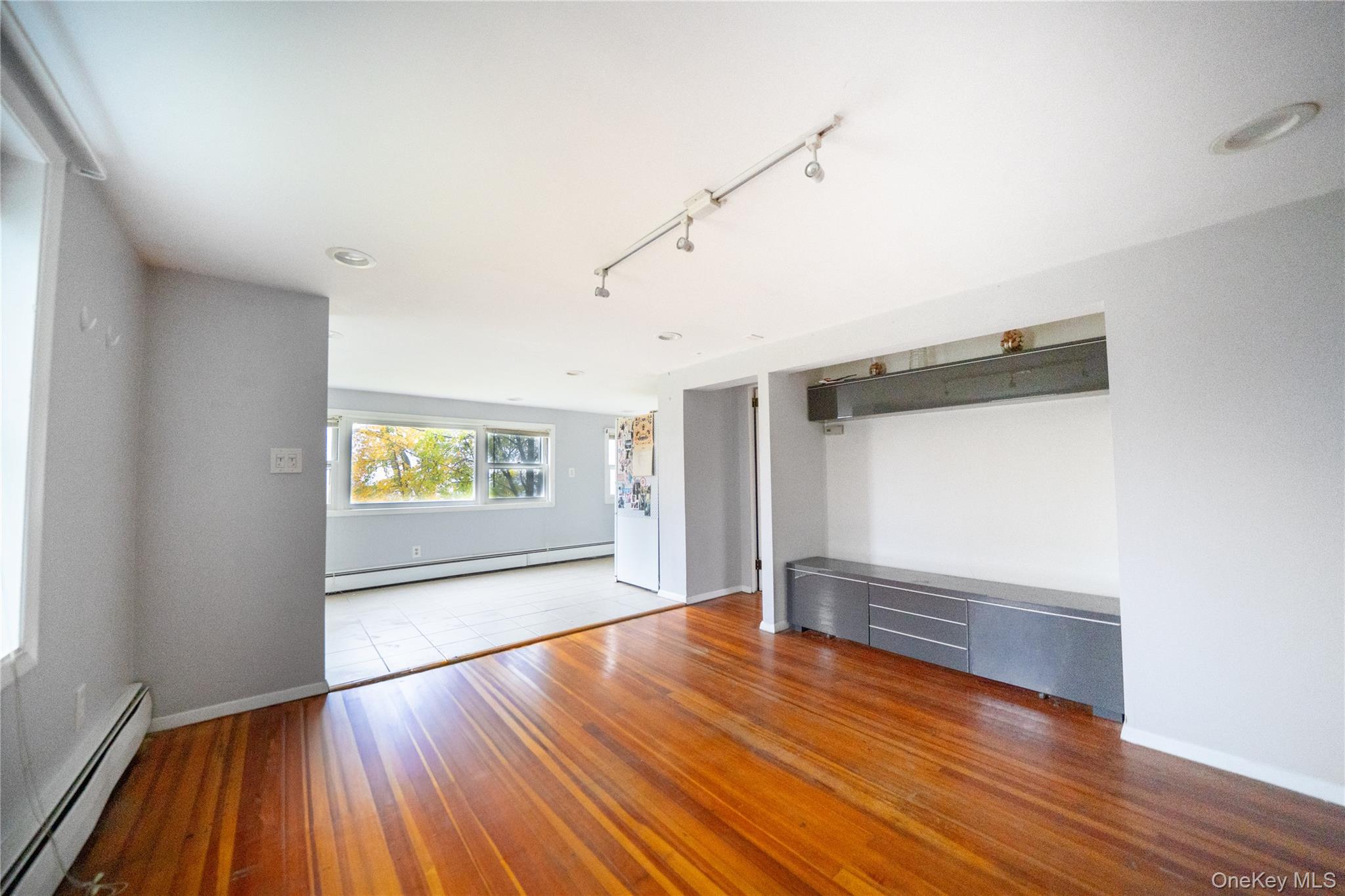 a view of empty room with wooden floor and window