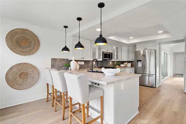 a open kitchen with stainless steel appliances granite countertop a stove a sink dishwasher a refrigerator with a dining table and chairs