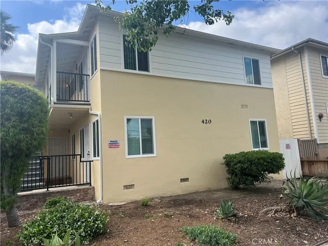 a view of a house with a yard and potted plants
