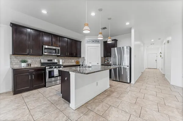 a kitchen with kitchen island granite countertop a sink stove and refrigerator