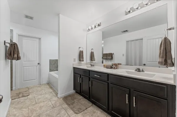 a spacious bathroom with a double vanity sink a mirror and a bathtub