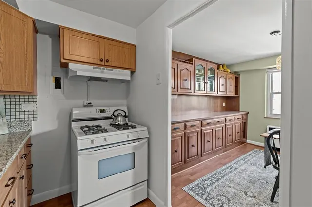 a kitchen with stainless steel appliances granite countertop a refrigerator a stove a sink a dining table and chairs