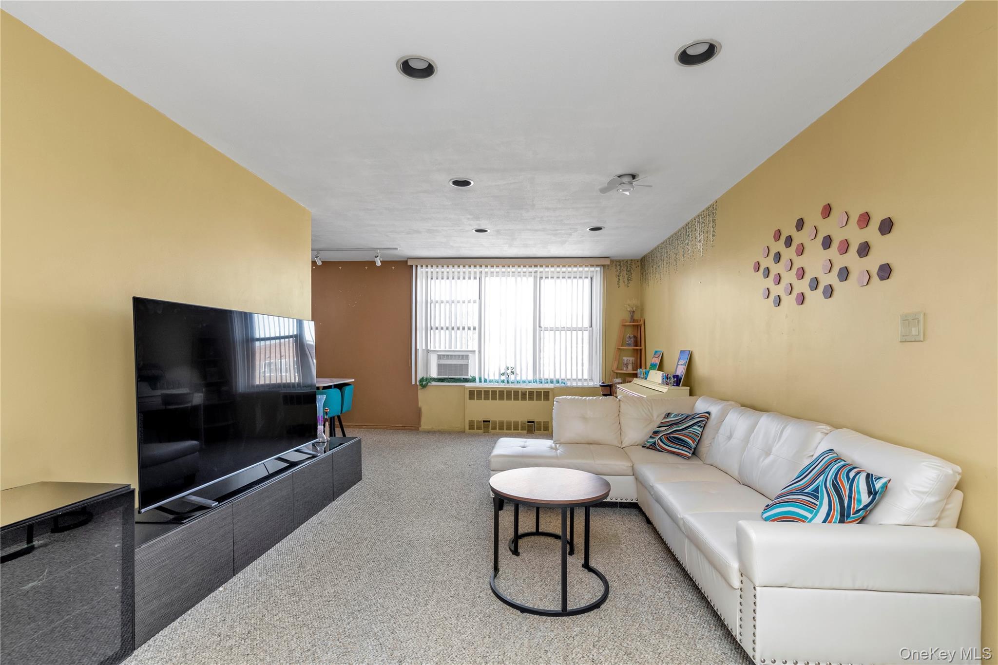 209-20 18th Avenue, Unit 6C Queens, NY 11360 - Photo 2 of 15 a living room with furniture and a flat screen tv