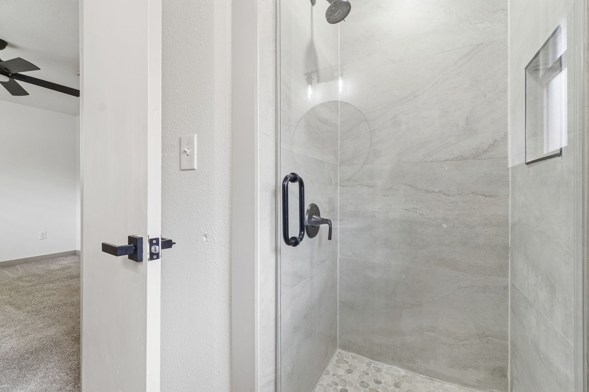 14850 Coaltown Road Willis, TX 77378 - Photo 25 of 41 Beautiful walk-in shower with sleek tile surround, pebble stone flooring, glass enclosure, and modern black fixtures.