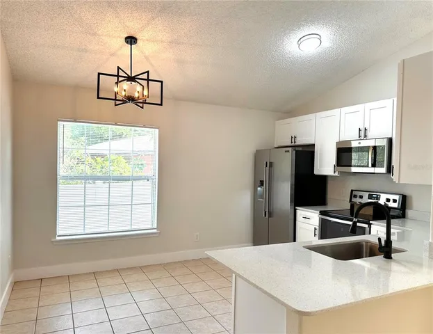 a kitchen with stainless steel appliances granite countertop a sink a stove a refrigerator a microwave with white cabinets and wooden floor