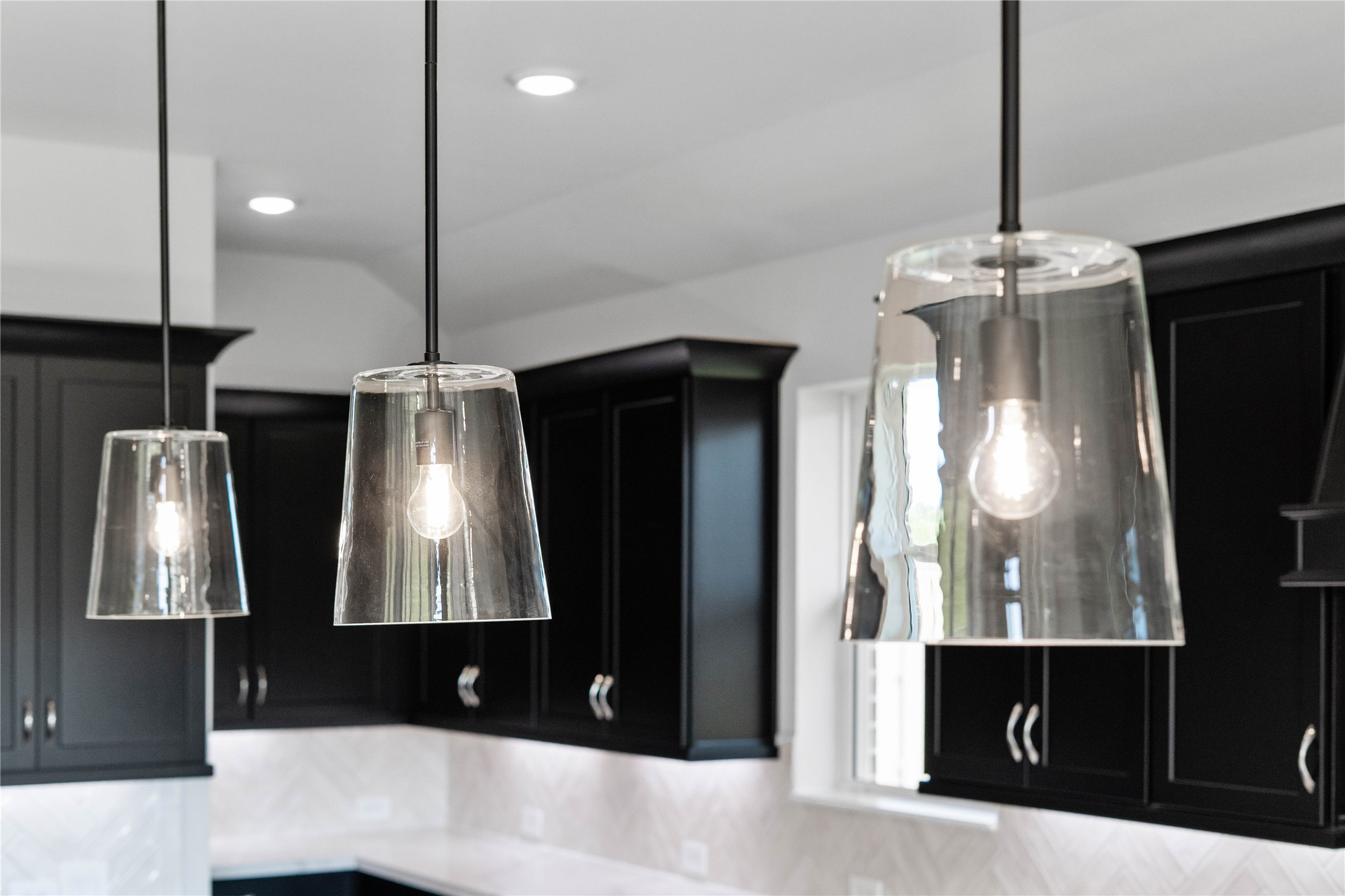 2114 Rowl Street Montgomery, TX 77316 - Photo 25 of 50 The island is anchored by a trio of statement glass pendant lights with matte black hardware, casting a warm glow.