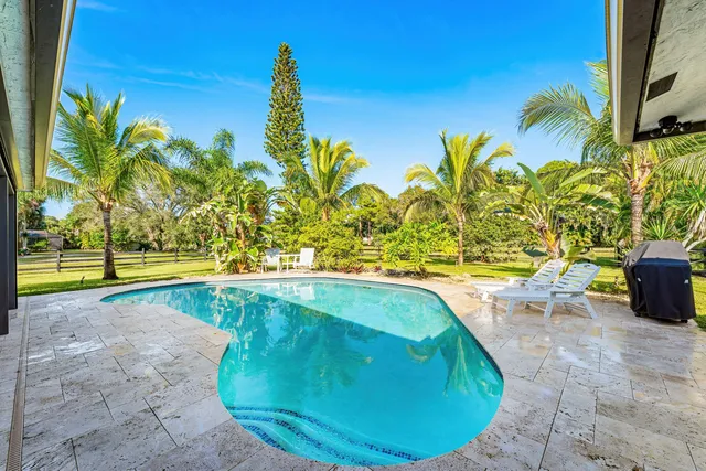 a view of a swimming pool with a yard and sitting area