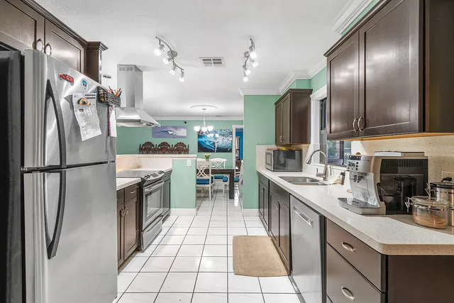 a kitchen with stainless steel appliances granite countertop a refrigerator a sink a stove and a refrigerator