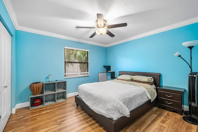a bedroom with a bed a dresser and wooden floor