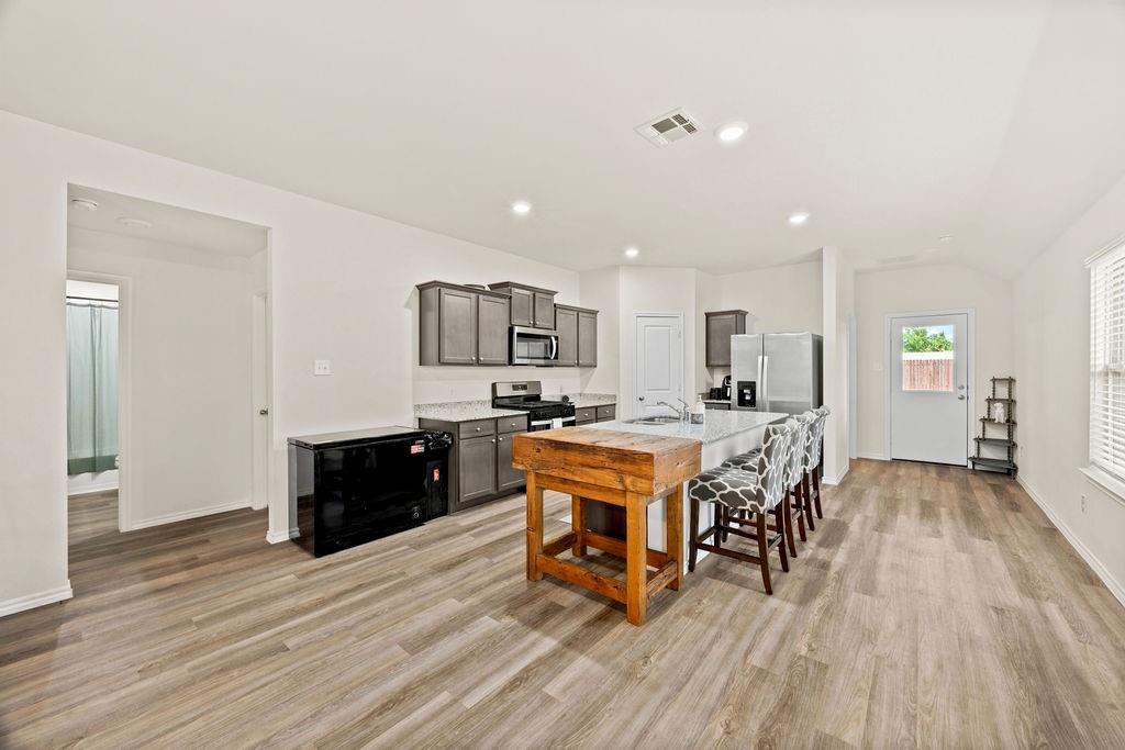 822 Ramble Road Lavon, TX 75166 - Photo 8 of 35 Open concept living space featuring wood-finish flooring, recessed lighting, and a kitchen with gray cabinetry