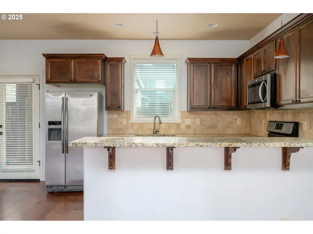 a kitchen with stainless steel appliances granite countertop a sink a stove and a refrigerator