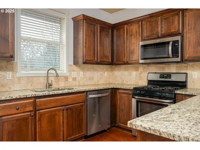 a kitchen with stainless steel appliances granite countertop a sink stove and microwave