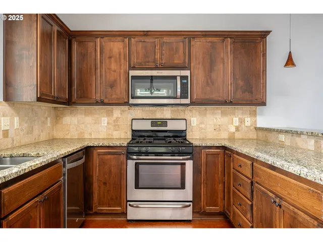 a kitchen with granite countertop wooden cabinets and stainless steel appliances