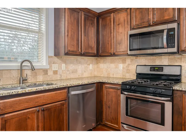 a kitchen with granite countertop wood cabinets and stainless steel appliances