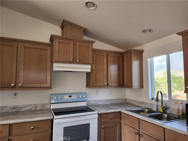 a kitchen with granite countertop a sink cabinets stainless steel appliances and a window