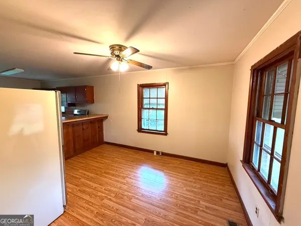 a view of an empty room with window wooden floor and a kitchen view
