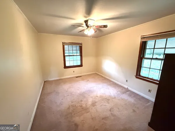 an empty room with windows and fan