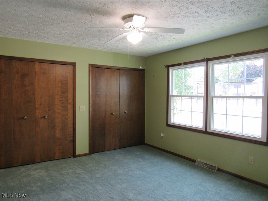 1120 Vincent Road Southeast North Canton, OH 44720 - Photo 37 of 50 Middle bedroom with a textured ceiling, new carpet, ceiling fan, and double closets