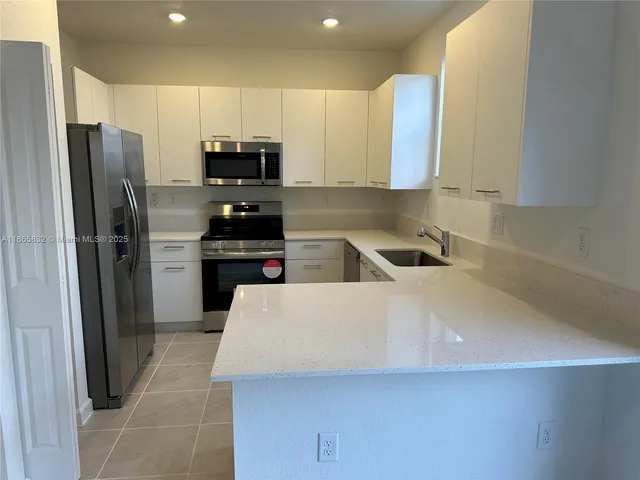 a kitchen with granite countertop a refrigerator and a sink