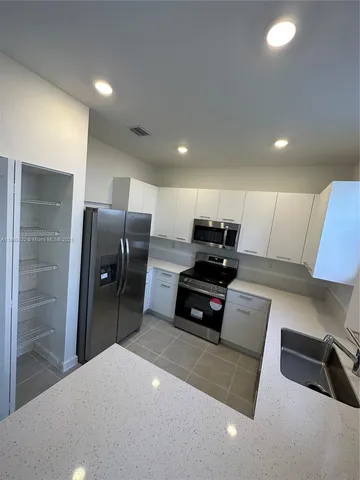 a large kitchen with kitchen island a sink a stove a counter space and cabinets