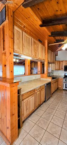 11785 Milam Road Colorado Springs, CO 80908 - Photo 28 of 44 Kitchen featuring light tile patterned floors, light countertops, stainless steel appliances, and wood ceiling