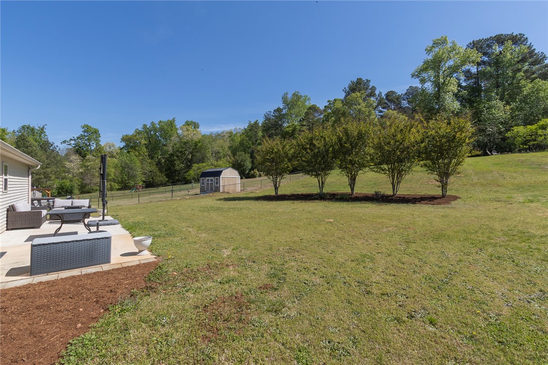158 Mediterranean Avenue Anderson, SC 29621 - Photo 38 of 39 Enjoy outdoor living in this expansive backyard featuring a patio, lush lawn, and mature trees.