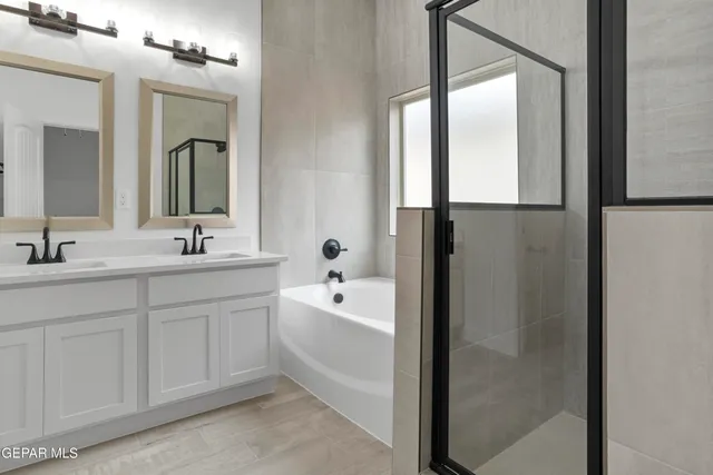 a bathroom with a double vanity sink mirror and bathtub
