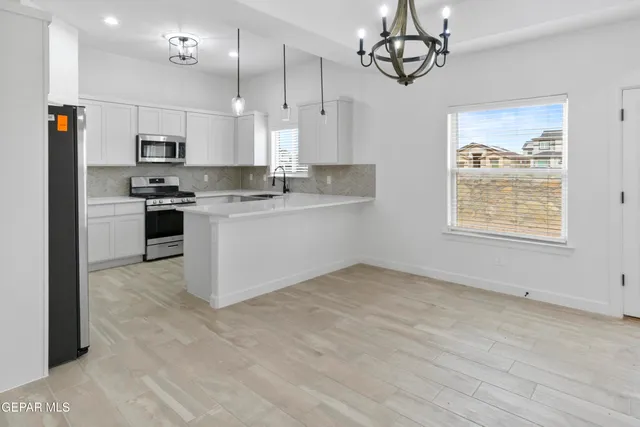 a kitchen with stainless steel appliances granite countertop a sink a stove a refrigerator and island with wooden floor