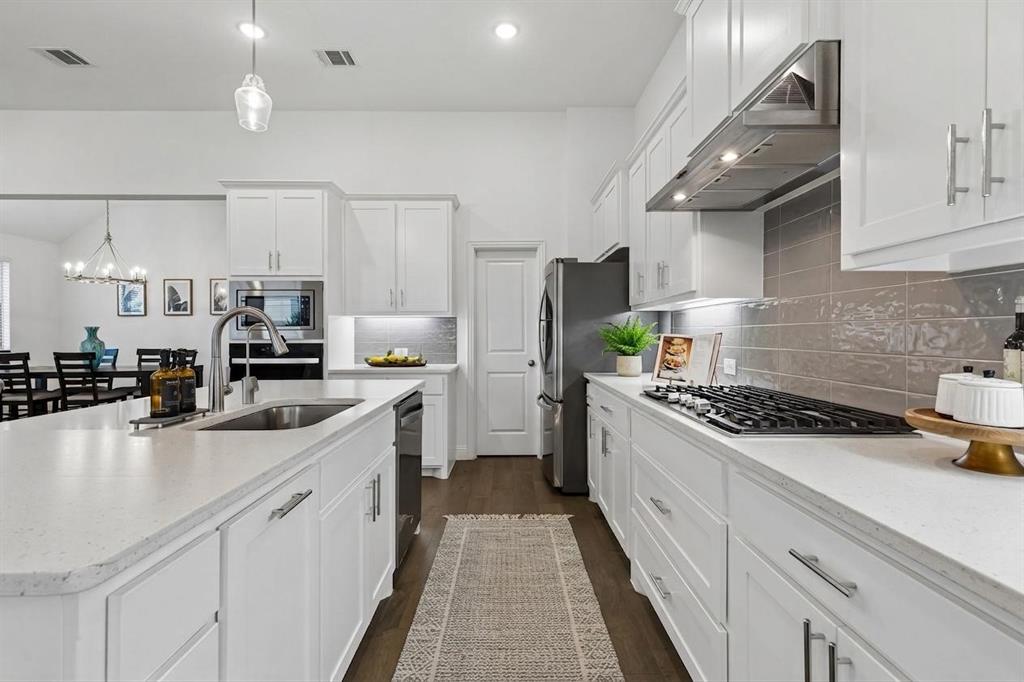 4933 Switchback Street Little Elm, TX 76227 - Photo 9 of 33 Easily store your pots and pans in the oversized drawers below the cooktop plus plenty of storage in the huge walk in pantry!