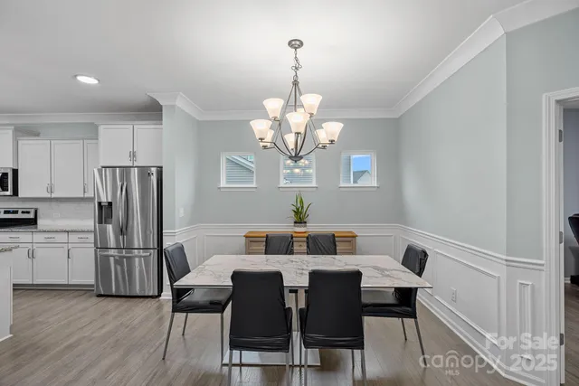 a view of a dining room with furniture a chandelier and wooden floor