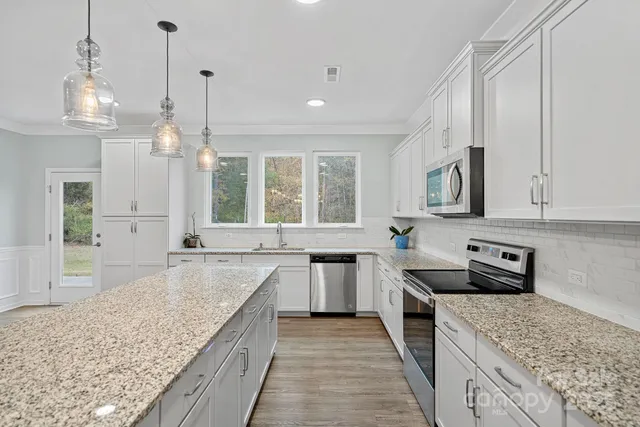 a kitchen with stainless steel appliances granite countertop a sink stove and refrigerator